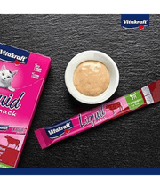 Vitakraft Liquid Snack Beef in a bowl with sachet on a dark surface, ideal for cat digestive support.