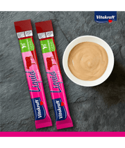 Vitakraft Liquid Snack Beef sachets and creamy treat in bowl on slate background, digestive support for cats.