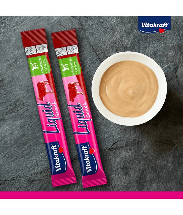 Vitakraft Liquid Snack Beef sachets and creamy treat in bowl on slate background, digestive support for cats.
