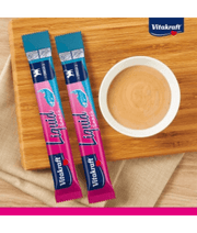 Vitakraft Liquid Snack Salmon sachets with creamy snack in bowl for cat skin and coat support.