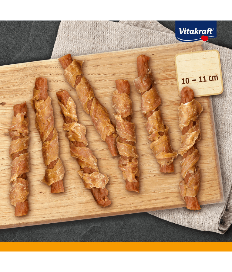 Vitakraft dog training treats, pure chicken twisted around carrot sticks, premium adult dog snacks on a wooden board.